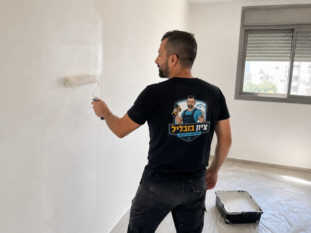 רולר צבע מעביר שכבה על קיר פנימי בהיר
